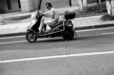 一名送餐員邊騎車邊看手機(jī)訂單。